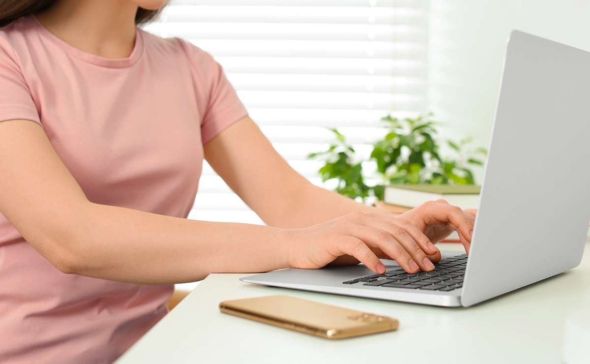 Mani su tastiera di un laptop durante la scrittura di contenuti digitali
