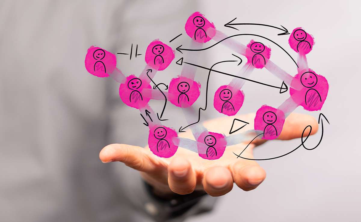 Mano aperta in primo piano che sostiene un’illustrazione con più figure umane stilizzate in rosa