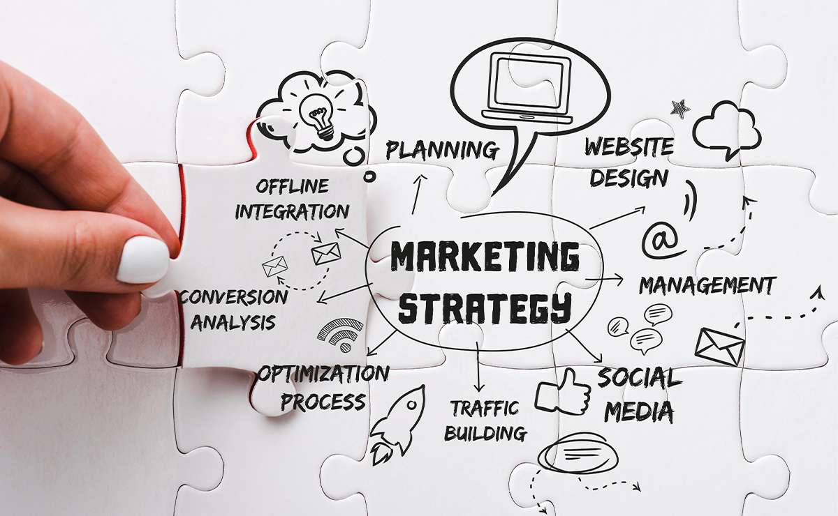Mano che completa un puzzle con la scritta “marketing strategy” al centro
