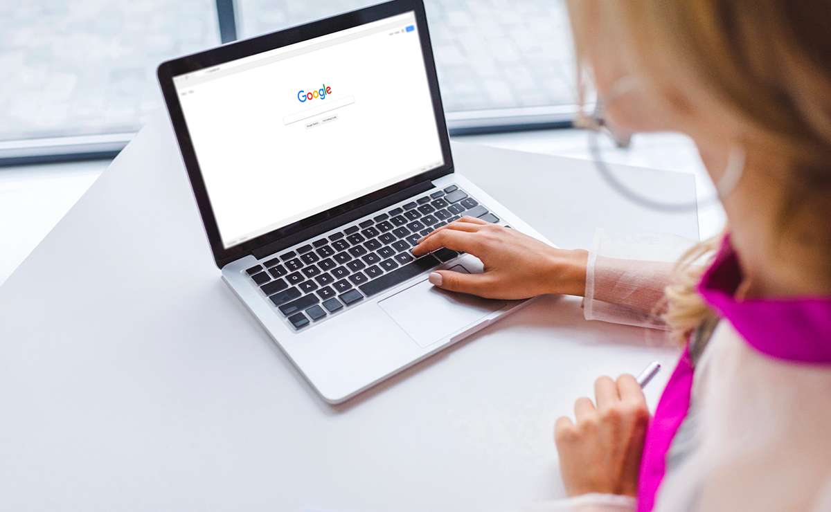 Persona che utilizza un laptop su una scrivania luminosa mentre effettua una ricerca su Google