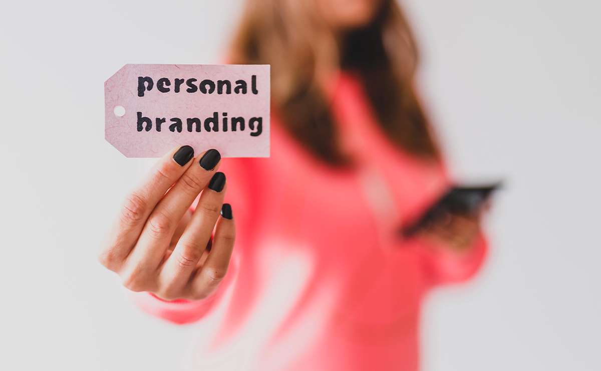 Cartellino con scritta personal branding tenuto in mano da una donna sfocata sullo sfondo