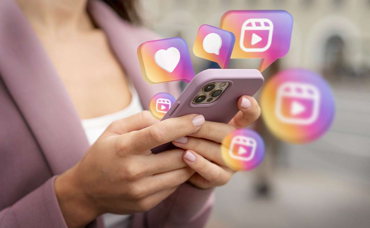 Mani di una persona che tengono uno smartphone mentre sullo schermo compaiono icone social